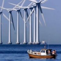 wind turbines in sea with boat in foreground